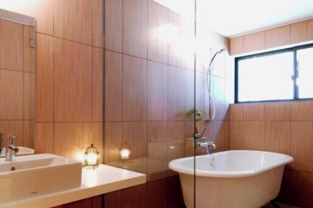 Ein modernes Badezimmer mit Holzvertäfelung, einer freistehenden Badewanne und einem großen Spiegel.