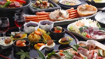 A variety of dishes and drinks on a table, including seafood, vegetables, and possibly sushi.