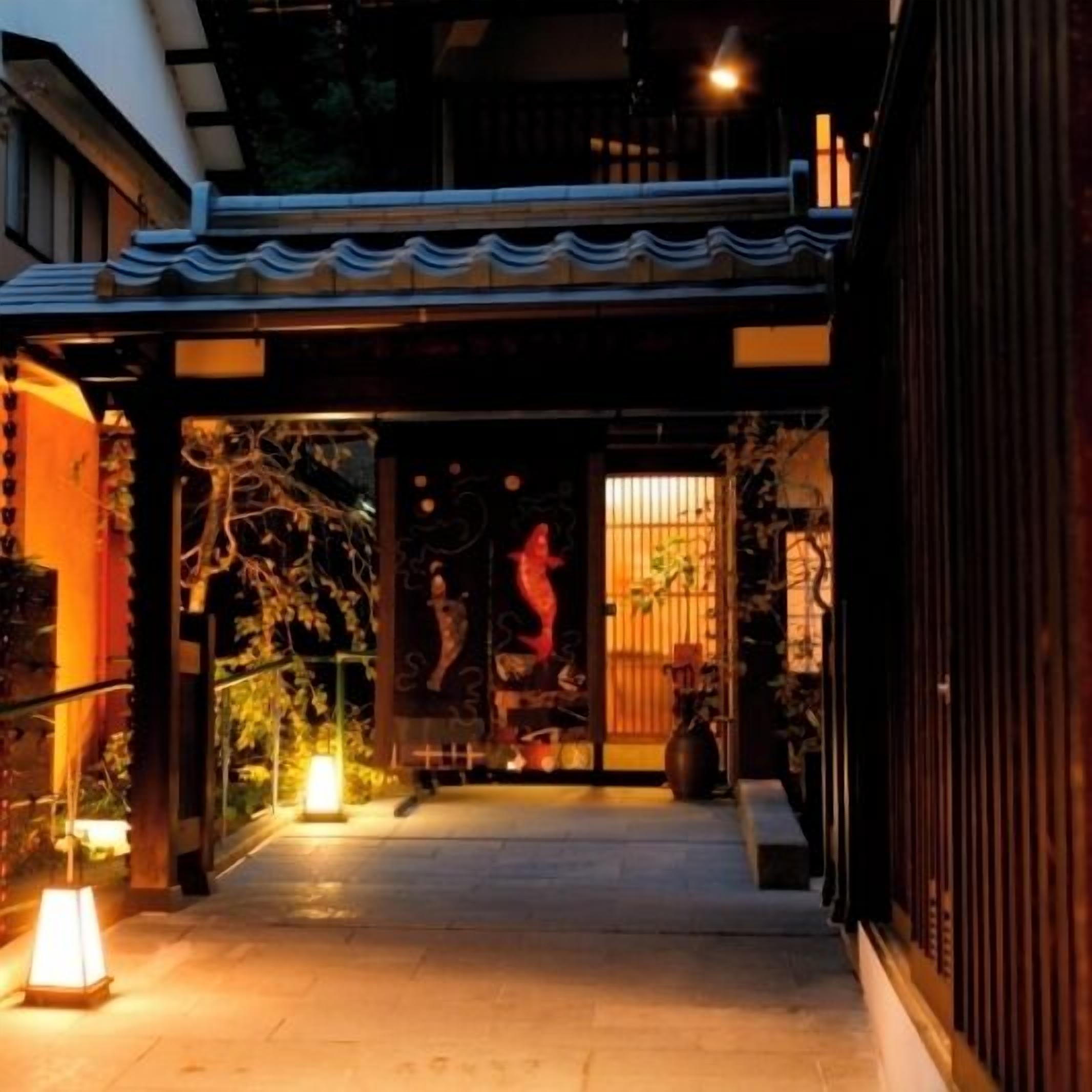 Une entrée de style japonais traditionnel, avec un chemin dallé menant à une porte en bois.