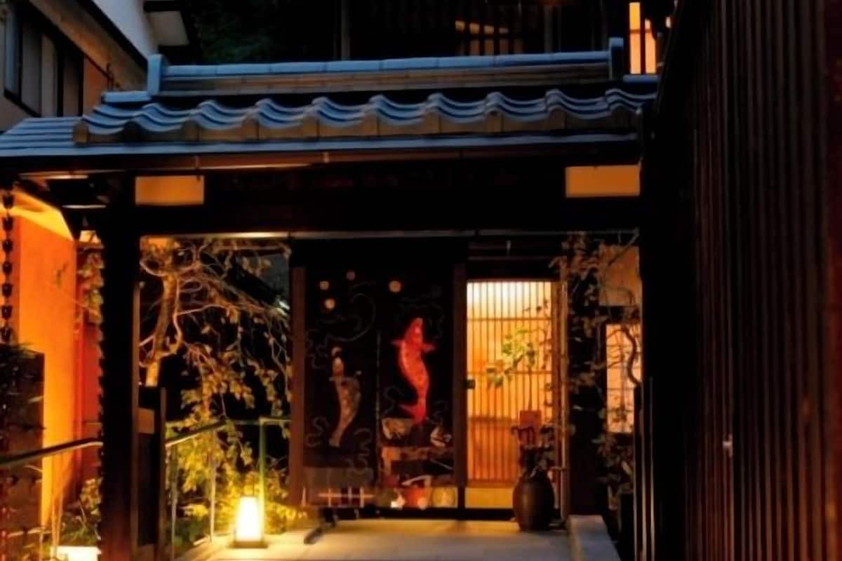 Ein traditioneller japanischer Eingangsbereich mit einem mit Fliesen ausgelegten Weg zu einem Holztor.