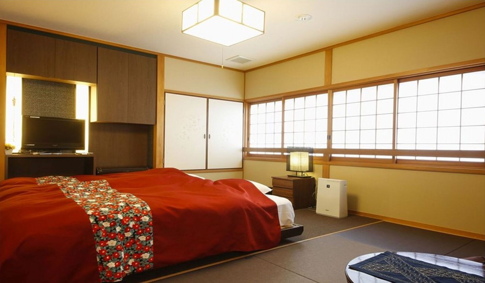 Une chambre de style japonais traditionnel, comprenant un lit, une armoire, un téléviseur et un futon.