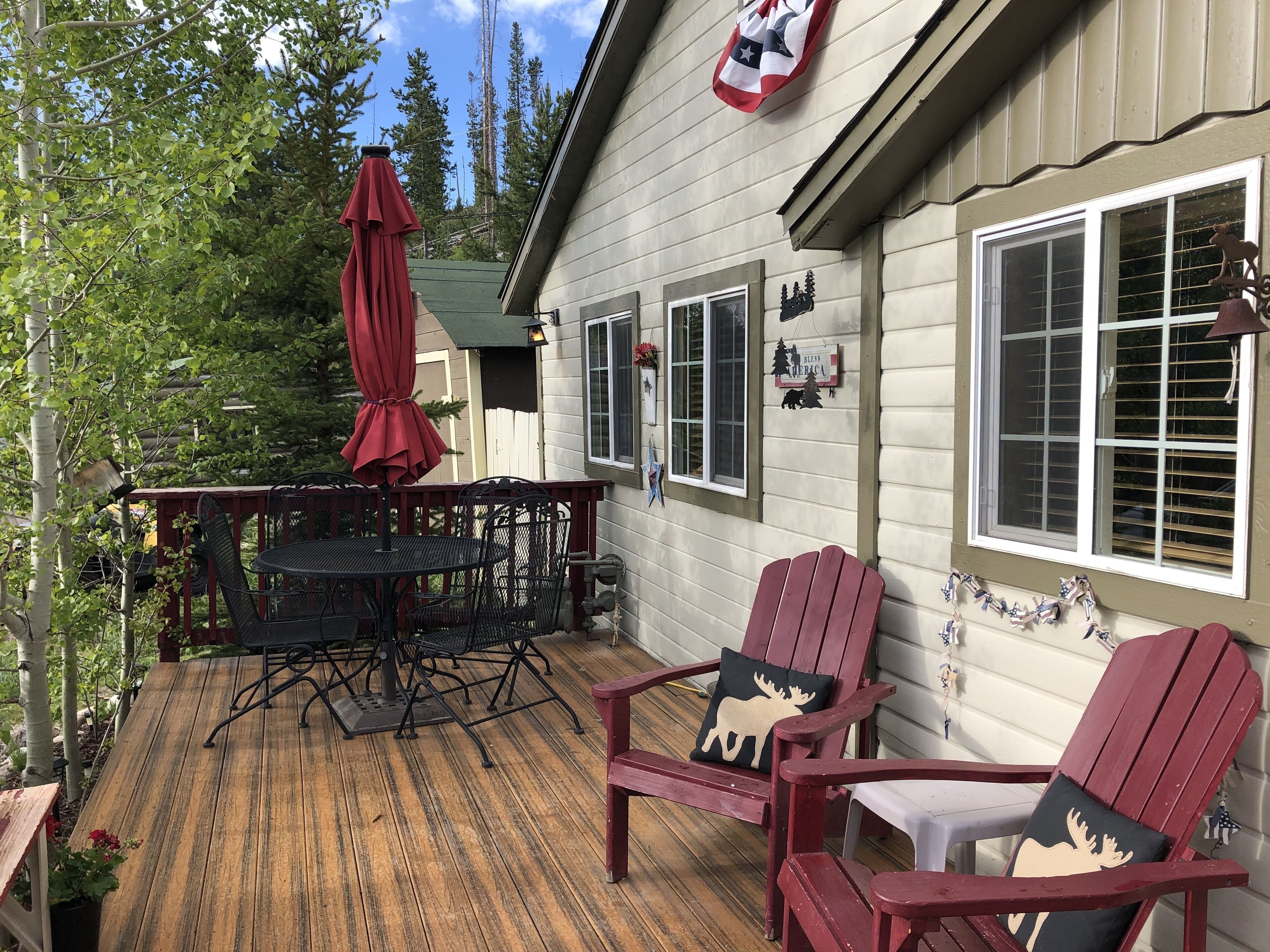 A wooden deck with a table and chairs, surrounded by trees.