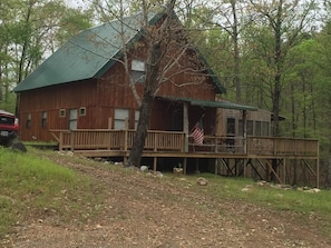 A rustic wooden cabin with a green roof, a porch, and an American flag. - Remote getaway-the national forest-Direct access to the ATV trails- Wolf Pen Gap (Mena)
