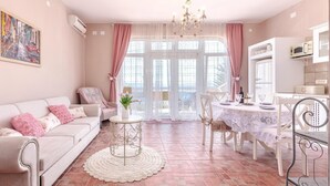 A cozy living room with a sofa, a dining table set for four, and a kitchen area with a microwave. - Awesome apartment in Dramalj with sauna (Dramalj)