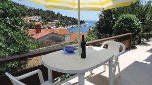 Un balcon avec une table, des chaises, une bouteille de vin et un parasol à rayures.