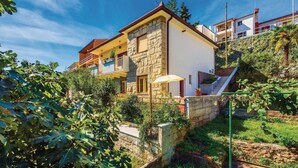 Une maison à deux étages avec une façade en pierre, des balcons et un jardin.