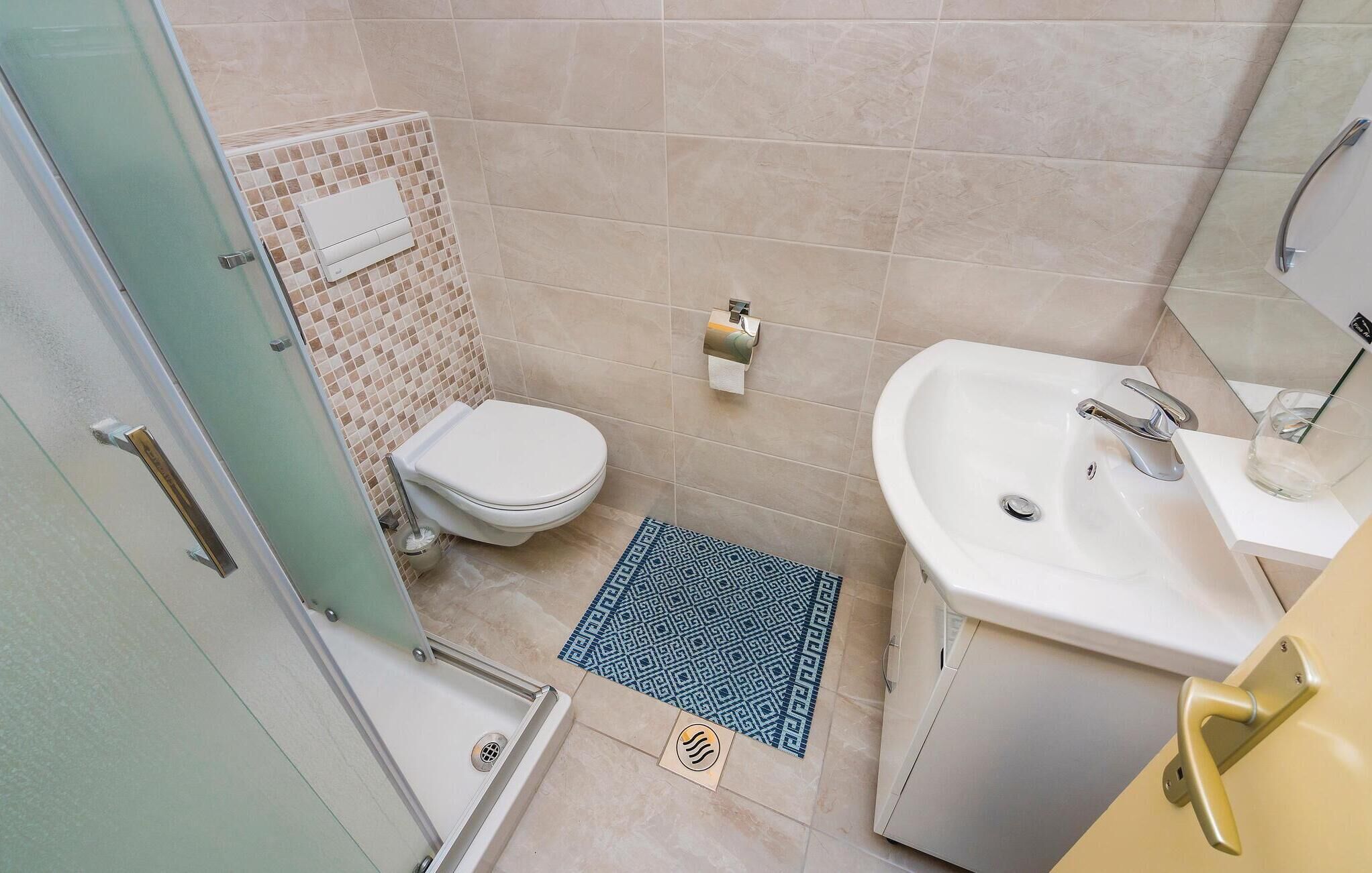 Une petite salle de bain avec des toilettes, un lavabo et une douche.