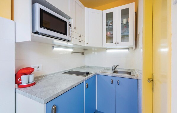 A compact kitchen with white and blue cabinets, a microwave, a coffee maker, and a sink. - 1 bedroom stunning apartment in Rabac (Rabac)