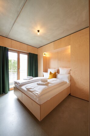 A modern bedroom with a large bed, wooden paneling, and a view through a sliding door. - Kitz Boutique Hotel & Restaurant (Metzingen)