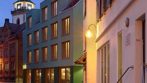 A building with a green facade, multiple windows, and a clock tower in the background. - Kitz Boutique Hotel & Restaurant (Metzingen)