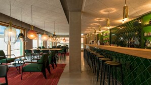 A modern bar area with green walls, multiple hanging pendant lights, and a long counter with stools. - Kitz Boutique Hotel & Restaurant (Metzingen)