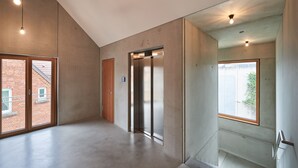 A modern interior with a concrete floor, a wooden door, and an elevator. - Kitz Boutique Hotel & Restaurant (Metzingen)