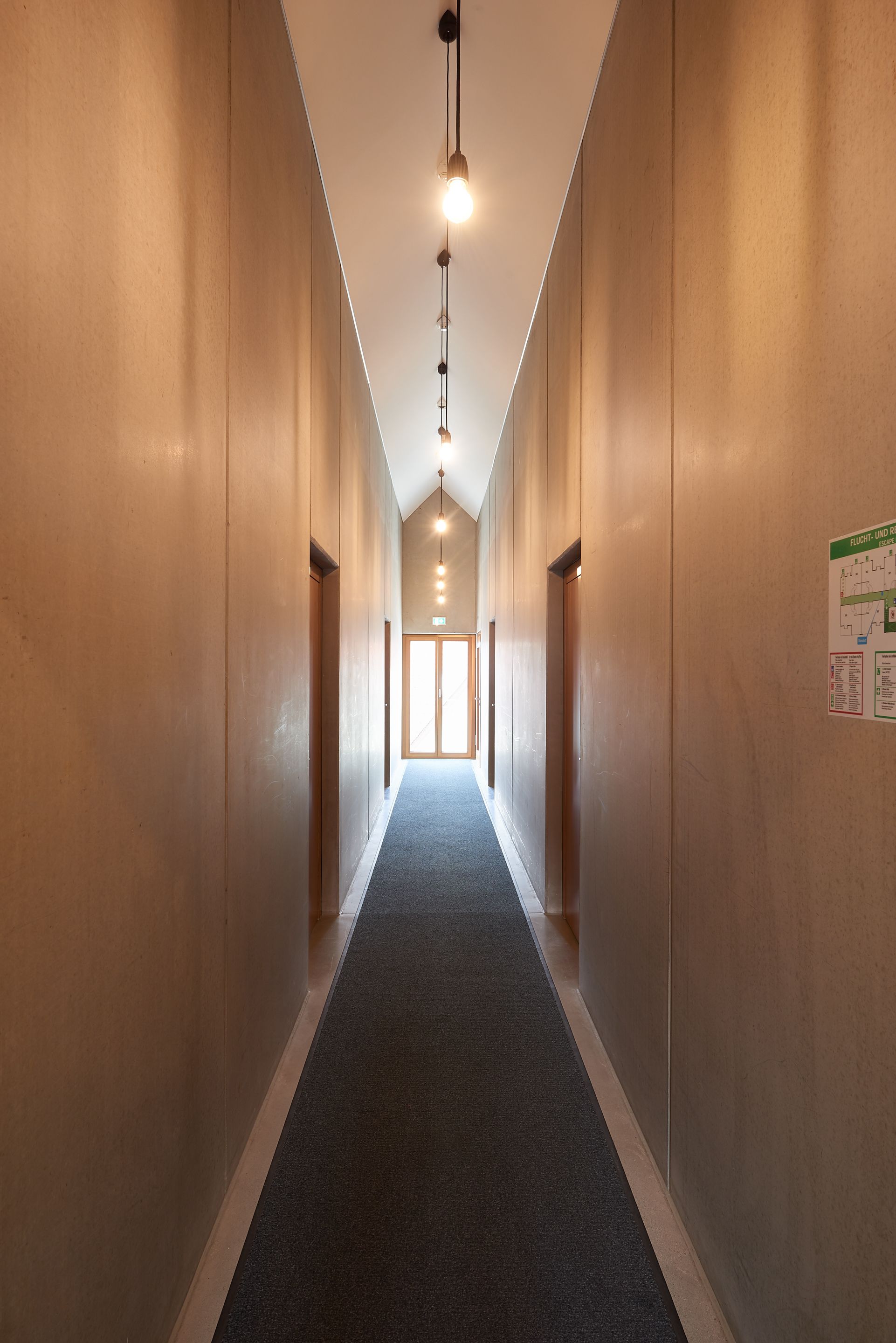 A long, narrow hallway with a carpeted floor and wooden walls.