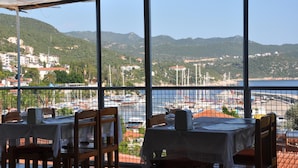 Un restaurant offrant une vue sur un port de plaisance et sur des collines.