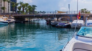 A marina with boats docked, a pedestrian bridge, and palm trees. - Augusta Apartment Jávea Sur, Stylish with AC, Wifi, Terrace and Pool (Javea / Xàbia)