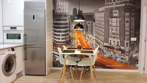 Une cuisine équipée d’un réfrigérateur moderne, d’un lave-linge et d’un coin repas avec une table et des chaises.