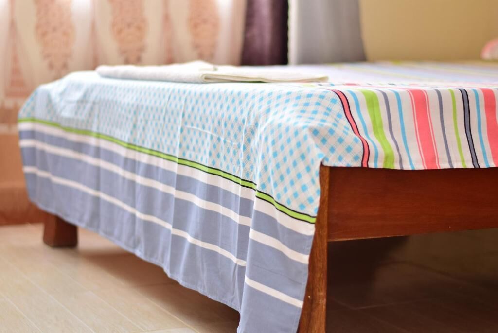 Un lit avec une couvre-lit à rayures et un coussin coloré à rayures.