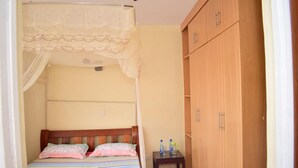 A bedroom with a bed, a nightstand, and a wardrobe. - Joy Comfort Homestay (Syokimau)