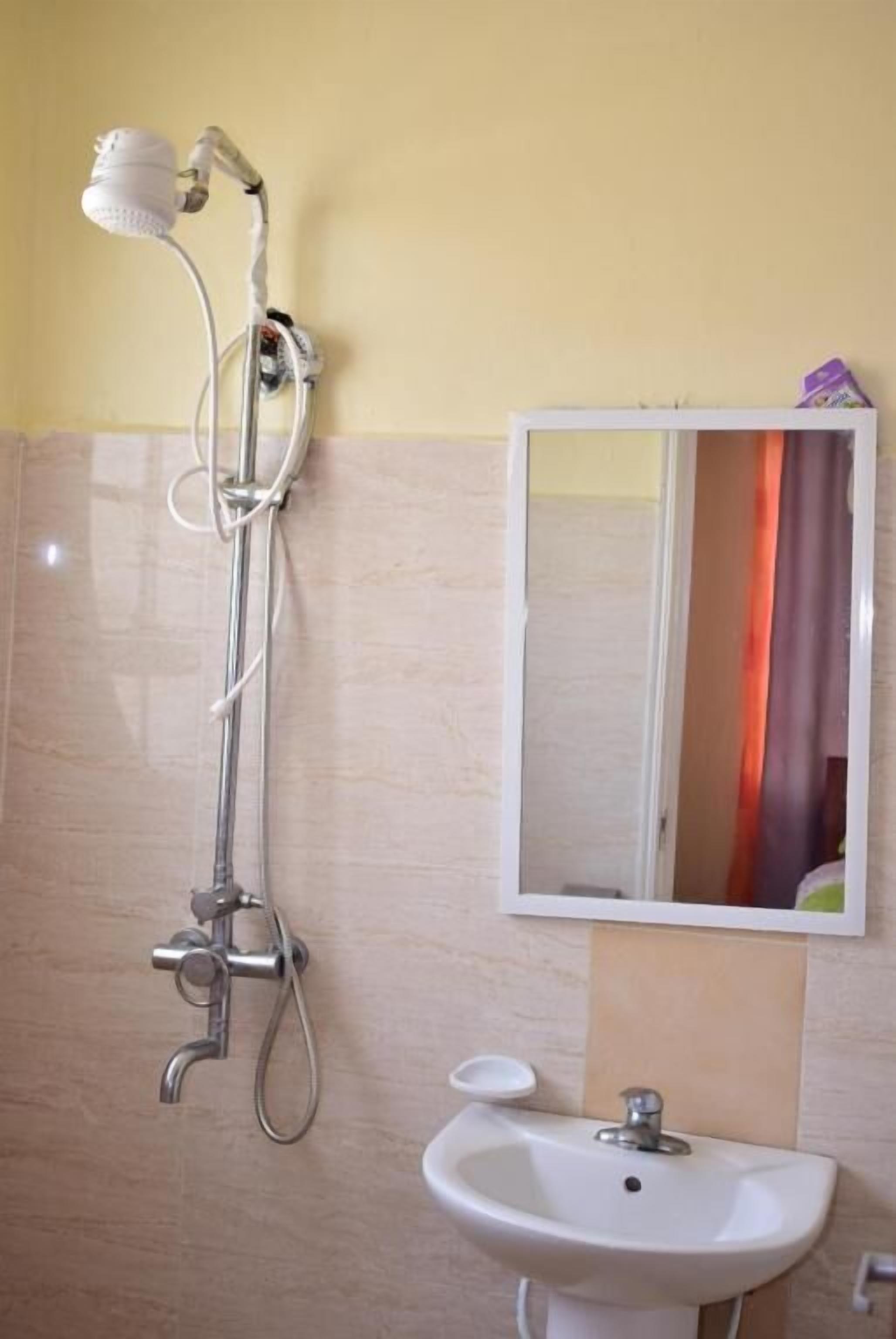 A bathroom with a shower, sink, and mirror.