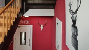 Una escalera con escalones de madera y una pared roja. Se ve una puerta blanca al final.