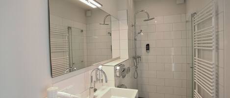 A modern bathroom with a large mirror, a sink, a toilet, and a shower area.