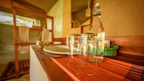 Une table en bois, avec une bouteille et des verres, évoquant un coin repas dans un cadre rustique.