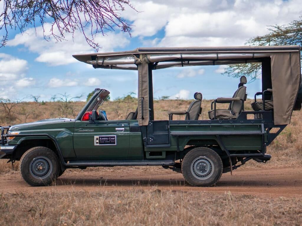 Un vehículo safari verde con techo, equipado con una mesita y dos asientos.
