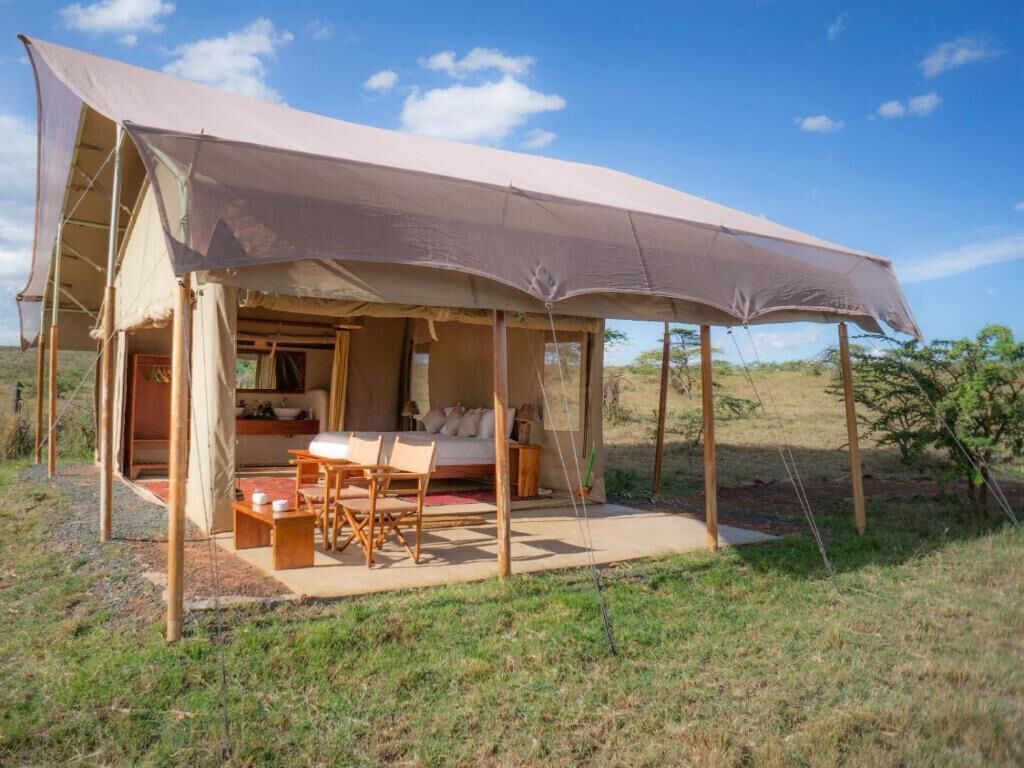 Una tienda safari con una cama, una mesa y sillas.