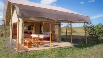 Una tienda safari con una cama, una mesa y sillas.