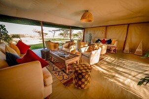 A spacious living area with a sofa set, a coffee table, and a patterned ottoman.