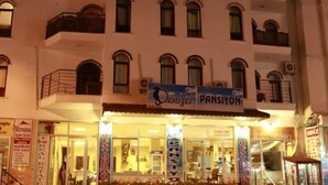 Un edificio con varias fachadas, que incluye un restaurante llamado 'Pansiyon' y una agencia de bienes raíces.