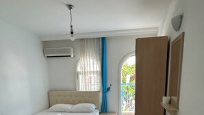 Un dormitorio con cama, una mesita, un espejo y una puerta que da a un balcón.