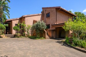 A two-story building with a flat roof and a small balcony. There are steps leading to the entrance, and the building is surrounded by greenery. - San Lameer Villa Rentals 10304 (Southbroom)