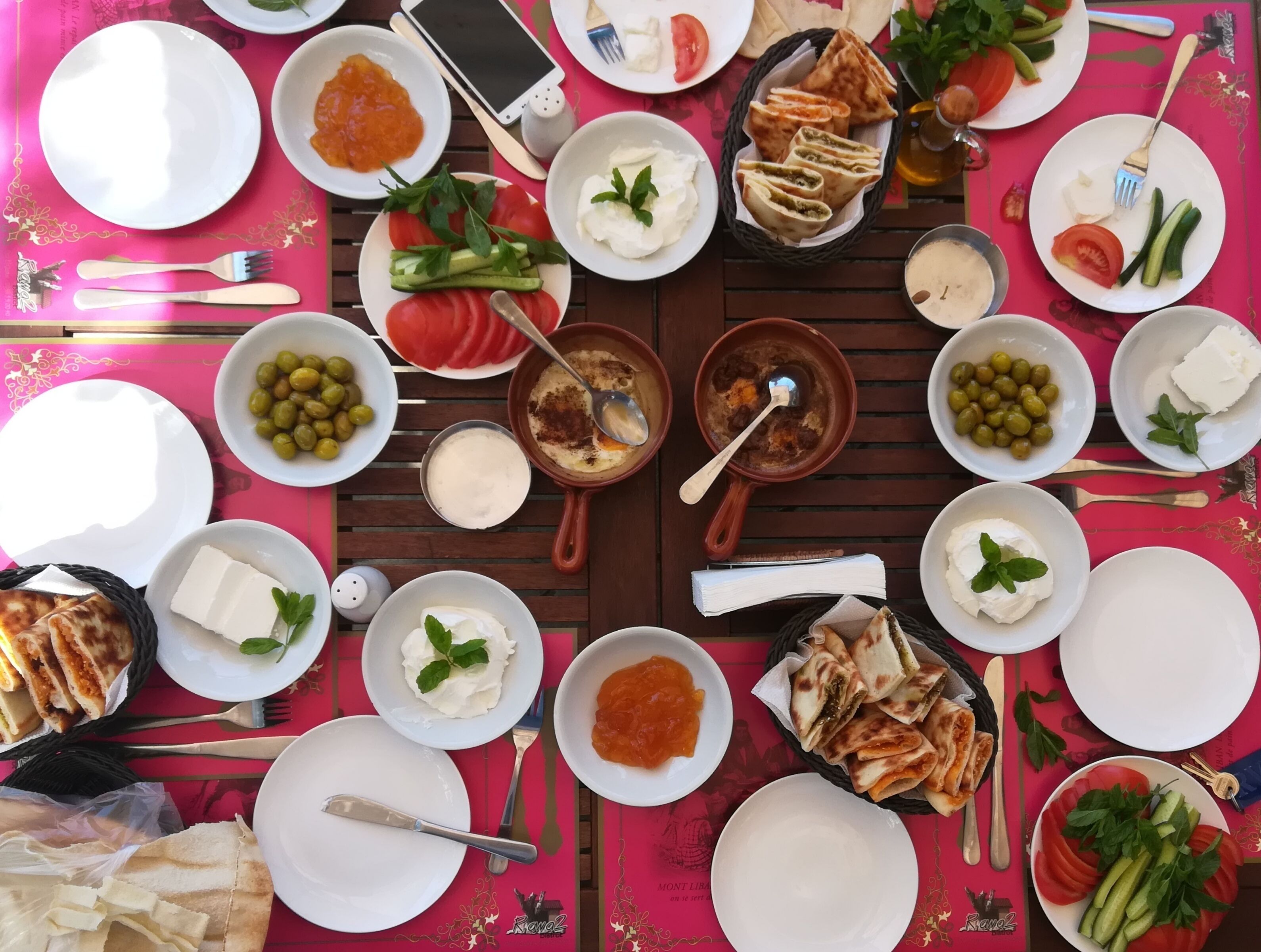 A table set with various dishes including bread, cheese, olives, and vegetables, suggesting a meal setup.