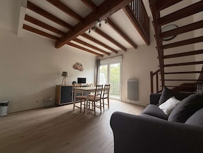 A room with a dining table, chairs, a sofa, a TV, and a window with a view. - Charming duplex for 4, near beach and port, La Rochelle (La Rochelle)