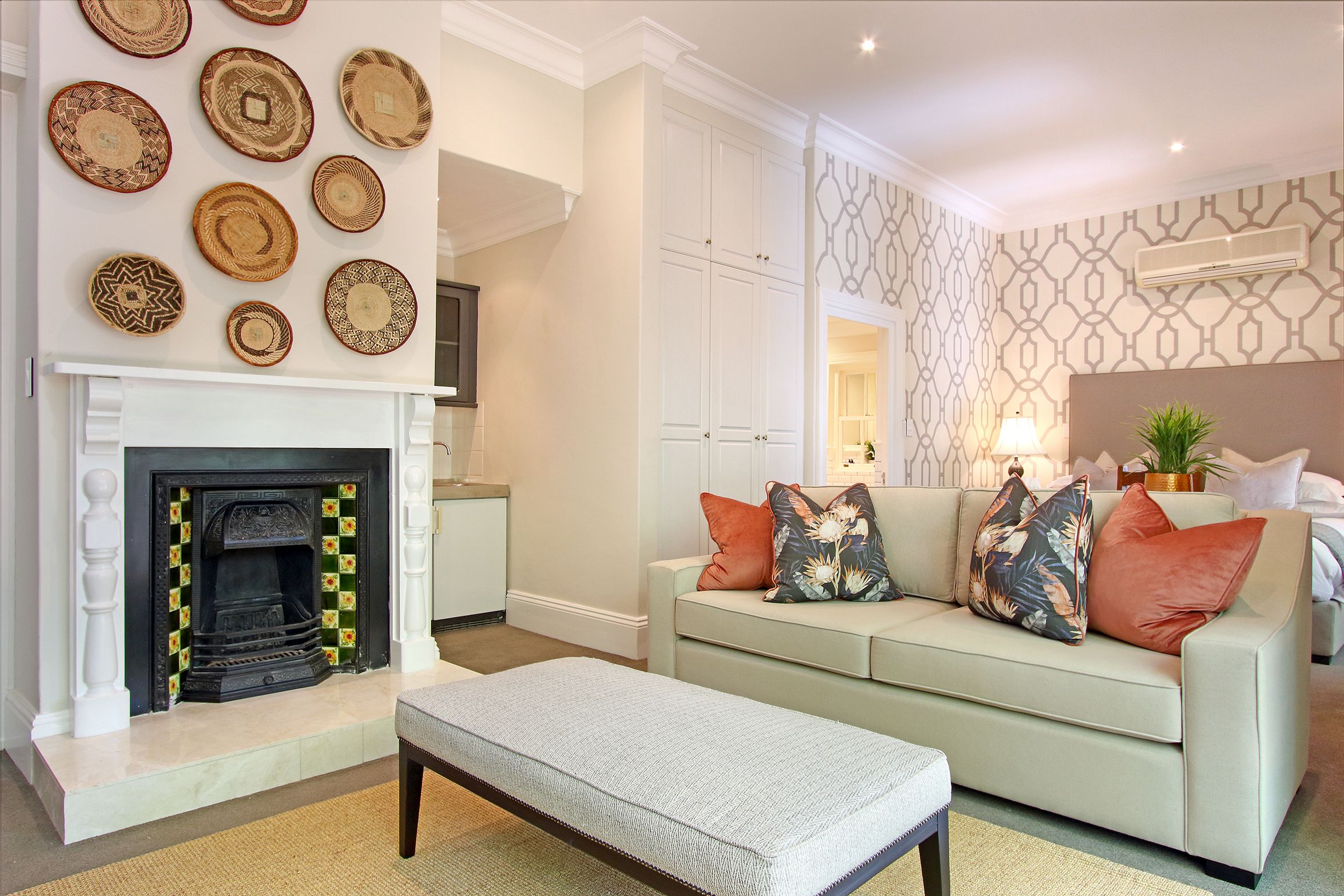 A living room with a fireplace, a sofa with cushions, a coffee table, and a patterned wall.