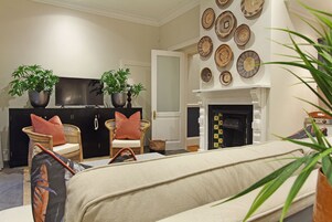 Una sala de estar con un sofá, dos sillones, un televisor de pantalla plana y una chimenea.