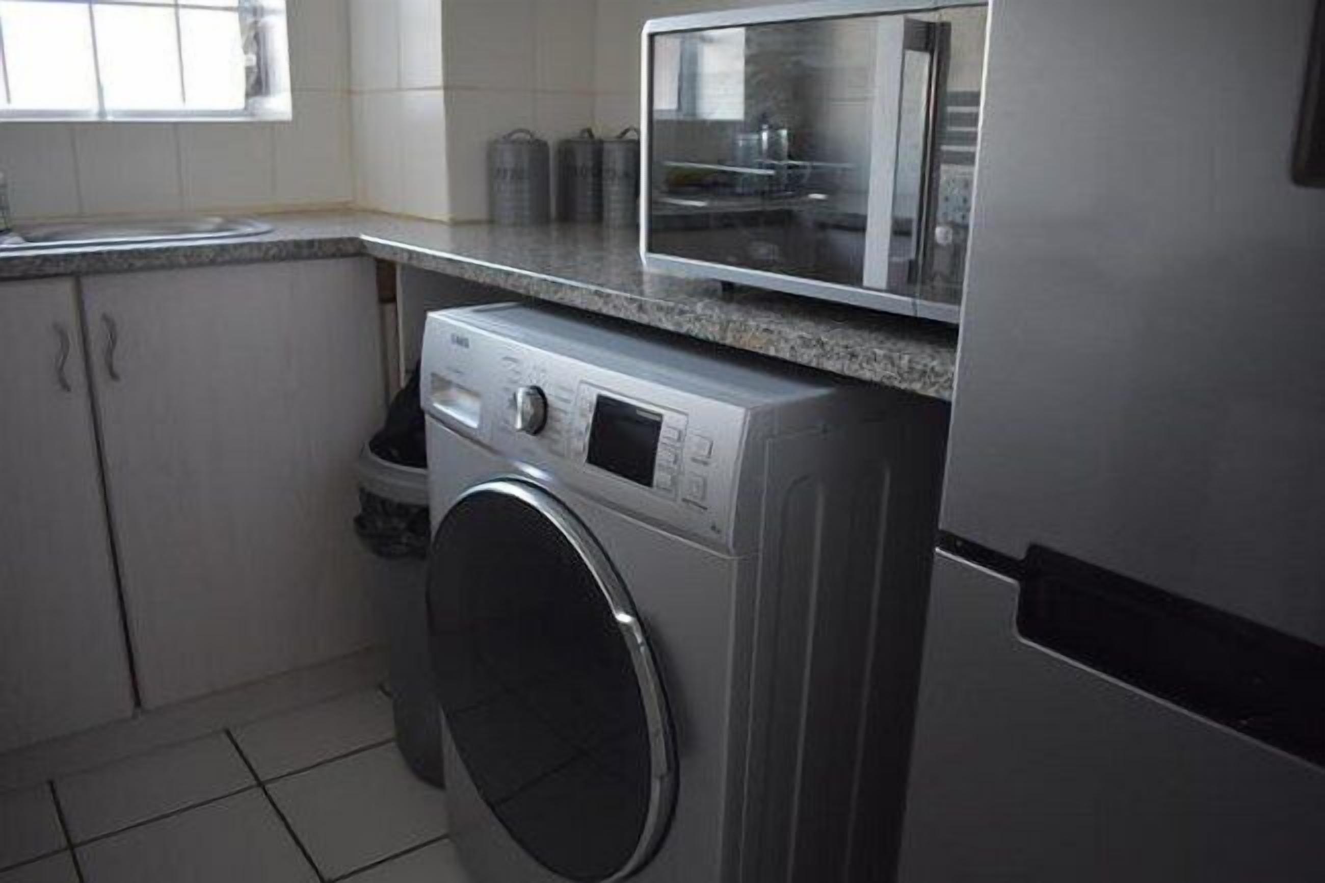 A compact kitchen with a washing machine, a microwave, and a sink.
