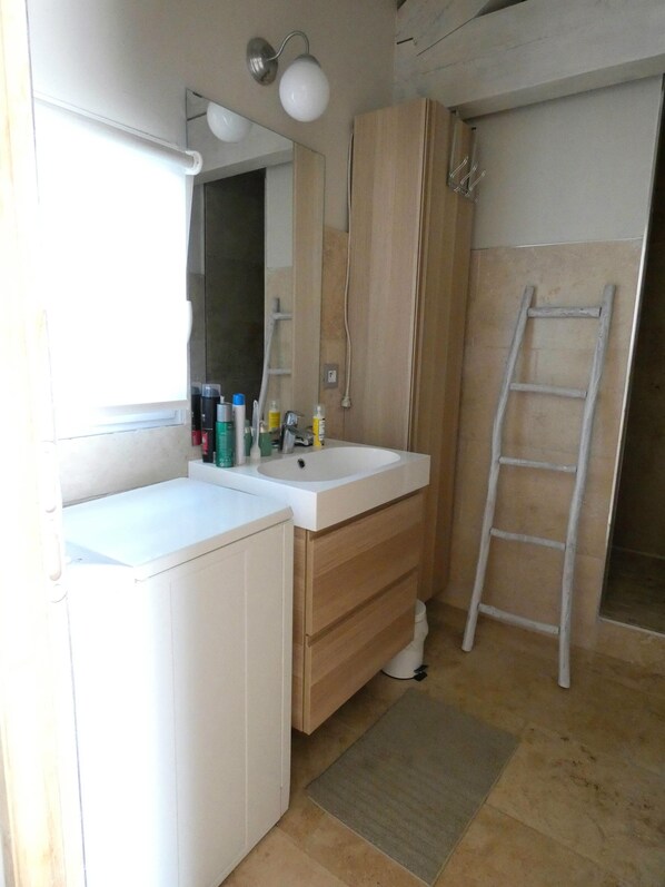 A bathroom with a white sink, wooden vanity, a mirror, and a shower area. - Cozy 2 room apartment with swimming pool (2/4 pers) (Fontvieille)
