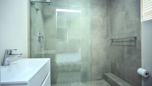 Un bagno moderno con cabina doccia in vetro, lavandino bianco e servizi igienici.