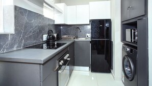 Una cucina moderna con un frigorifero nero, un forno integrato e una lavatrice.