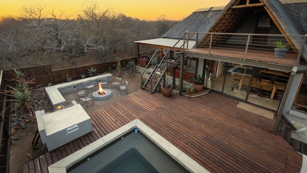A modern house with a wooden deck, outdoor seating, and a hot tub. - Ntoma House (Hoedspruit)