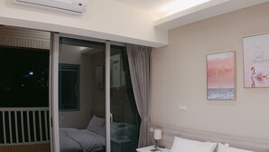 A hotel room with a bed, a nightstand, a lamp, a window with curtains, and a wall with a poster. - Shine Residence (Taichung)