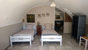Een knus slaapkamer met twee bedden, een klein nachtkastje met lamp, een spiegel en een kledingkast.