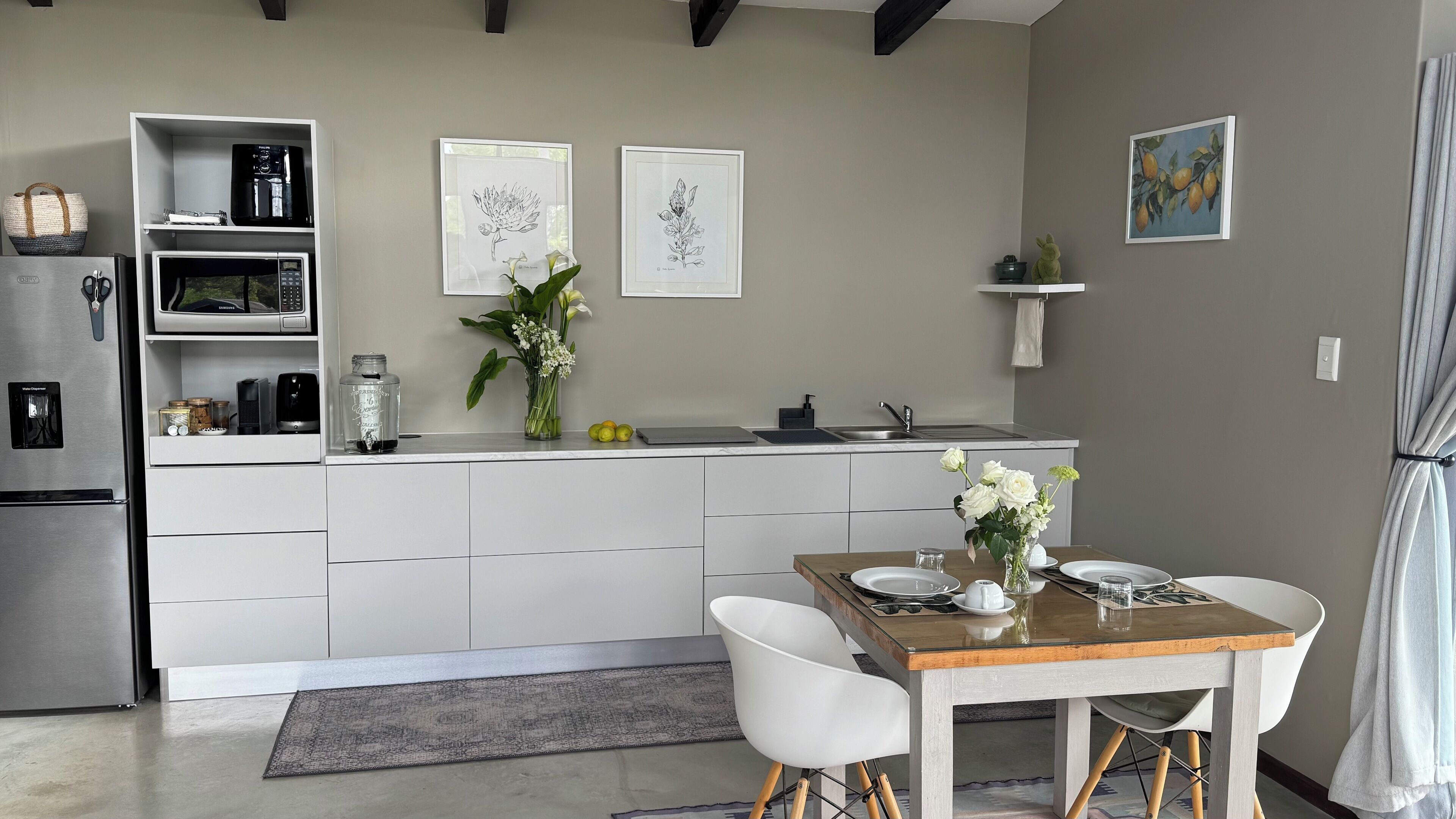 A modern kitchen with white cabinetry, a dining table with chairs, and artwork on the walls.
