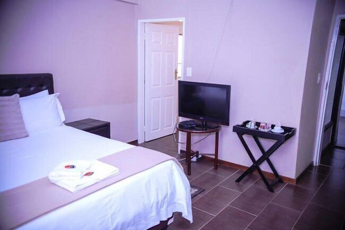 Une chambre d’hôtel avec un lit, une télévision et une petite table avec des articles de toilette.