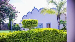 Un bâtiment doté d’un toit à la forme unique, orné de motifs en coquille, et d’une haie bien entretenue en premier plan.