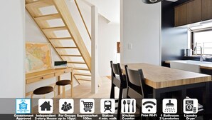 Une cuisine moderne avec un escalier en bois, un coin repas et un coin cuisine. Elle comprend des équipements tels qu’un plan de travail, une connexion Wi-Fi gratuite et un sèche-linge.