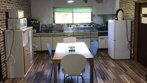 A compact kitchen with a dining area, featuring a sink, stove, microwave, and refrigerator. - Airfield hill and patchwork hill valley house (旭川市)