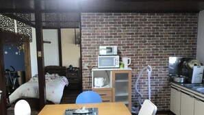 A compact kitchen with a brick wall, a microwave, a kettle, and a sink. - Airfield hill and patchwork hill valley house (旭川市)